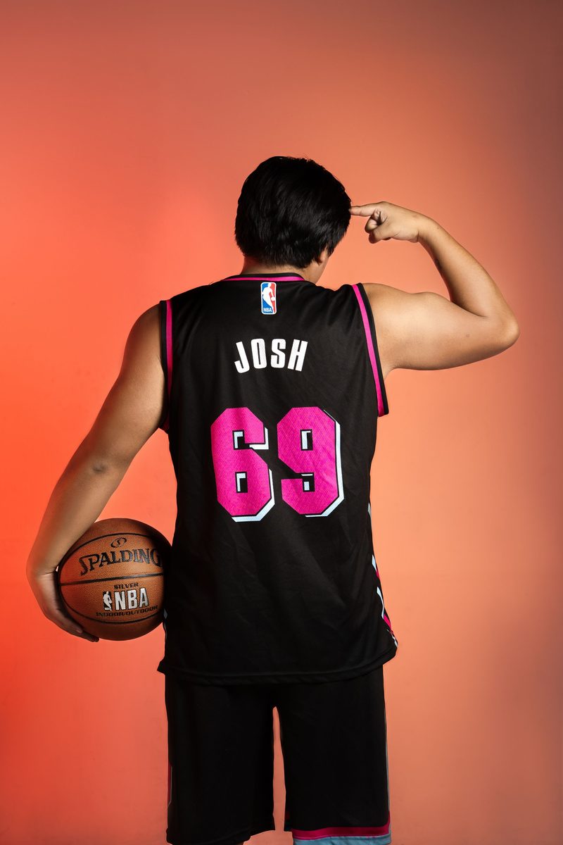Basketball player holding a ball and showing a custom jersey